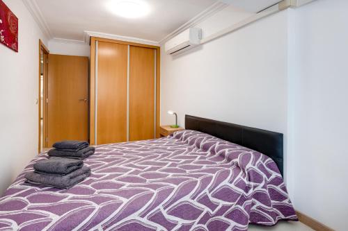 ein Schlafzimmer mit einem großen Bett mit einer lila Bettdecke in der Unterkunft Apartamento Boliche in Benimagrell