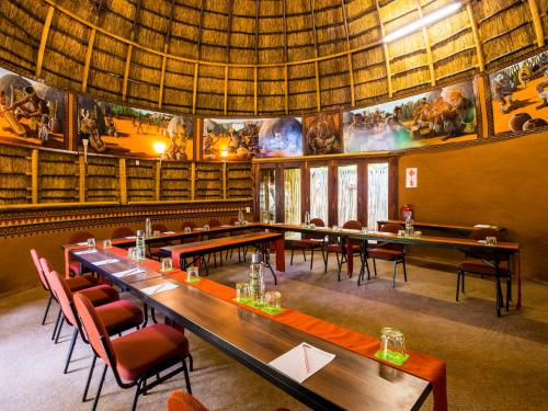 a restaurant with tables and chairs in a room with books at aha Lesedi African Lodge & Cultural Village in Pelindaba