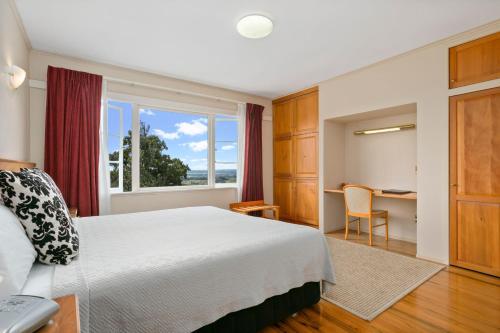 a bedroom with a bed and a window and a desk at Waitakere Resort & Spa in Auckland