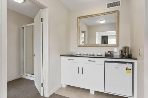 a white bathroom with a sink and a mirror at Waitakere Resort & Spa in Auckland