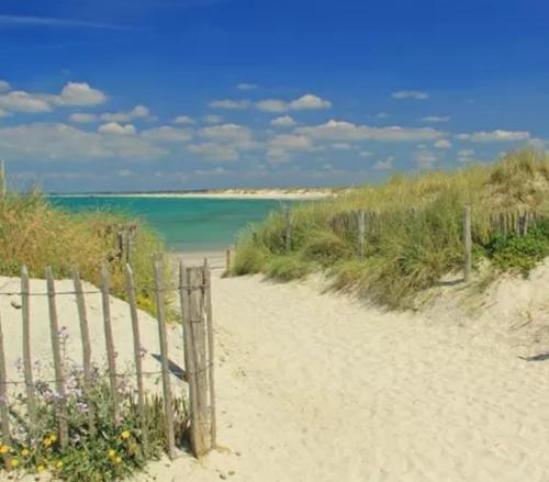 a fence on a sandy beach with the ocean at Ty Biz in Saint-Jean-Trolimon