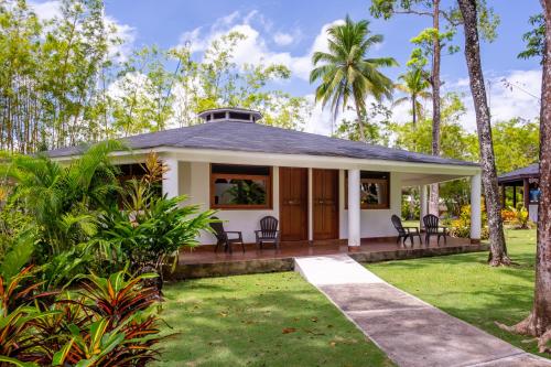 a house with a porch with chairs and trees at Nanajuana Río Dulce in Rio Dulce