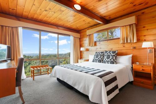 sypialnia z łóżkiem i dużym oknem w obiekcie Waitakere Resort & Spa w Auckland