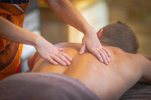 a man getting a back massage from a therapist at Au Jardin Des Colibris Ecolodge&Spa in Deshaies