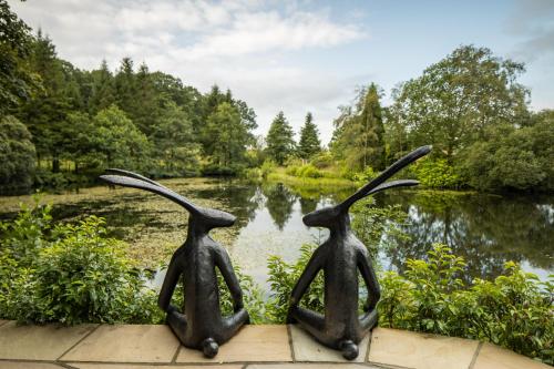 two statues of two people sitting in front of a pond at Linthwaite House Hotel in Bowness-on-Windermere