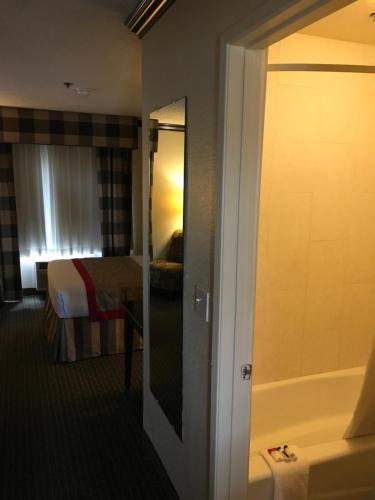 a hotel room with a bathroom with a bed and a tub at Ramada by Wyndham Ontario Airport & Convention Center in Ontario