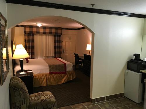 a hotel room with a bed and a desk at Ramada by Wyndham Ontario Airport & Convention Center in Ontario