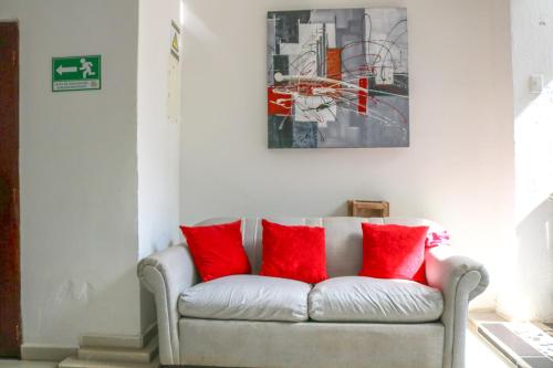 a couch with red pillows in a living room at Hotel Jardines Evans By GEH Suites in Mompos