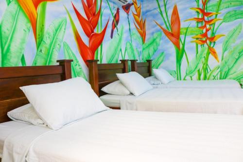 two beds in a room with a mural of plants at Hotel Jardines Evans By GEH Suites in Mompos