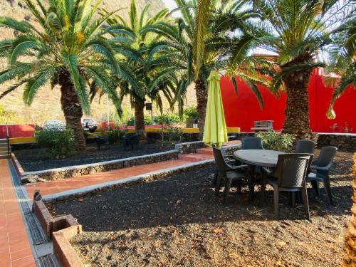 un patio con mesa, sillas y palmeras en Pensión Casa Trudo, en La Frontera