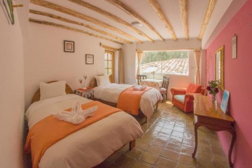 a room with three beds and a chair and a window at Parwa Guest House in Ollantaytambo