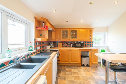 a kitchen with wooden cabinets and a sink and a table at Aye Stay Home, city centre in Inverness