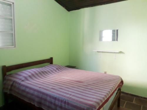 ein Schlafzimmer mit einem Bett mit einer lila gestreiften Decke in der Unterkunft CASA NO CENTRO DA CIDADE in Caraguatatuba