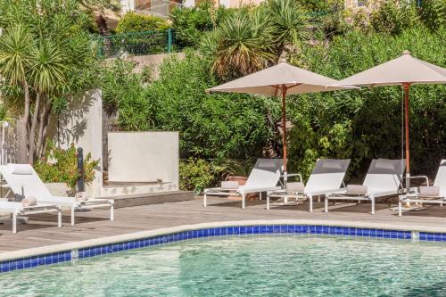 a pool with chaise lounge chairs and umbrellas at Best Western Hotel Matisse in Sainte-Maxime