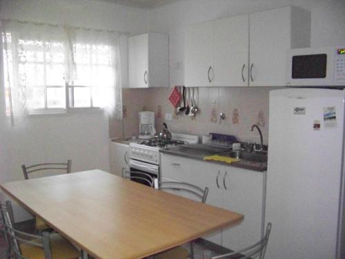 a kitchen with a table and a white refrigerator at Lejos de Pindal in Santa Clara del Mar