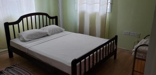 ein Bett mit weißer Bettwäsche und Kissen in einem Schlafzimmer in der Unterkunft Unit 2 Private Apartment - Roseau in Roseau
