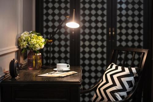 a table with a vase of flowers and a cup of coffee at Imperial Hotel & Spa in Hanoi