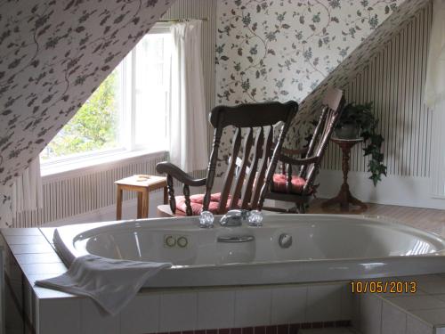 a bath tub in a room with two chairs at Louisbourg Harbour Inn in Louisbourg