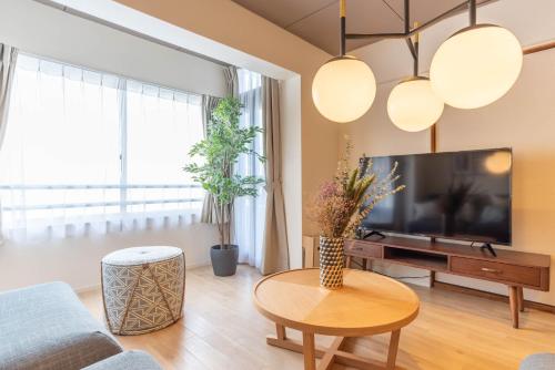 sala de estar con TV y mesa en Bijou Suites Pieces, en Osaka