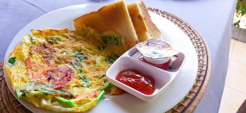 een bord eten met een omelet en een sandwich bij Bali Bhuana Beach Cottages in Amed