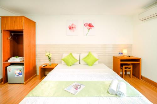 a bedroom with a white bed with green pillows at My Hotel in Quy Nhon