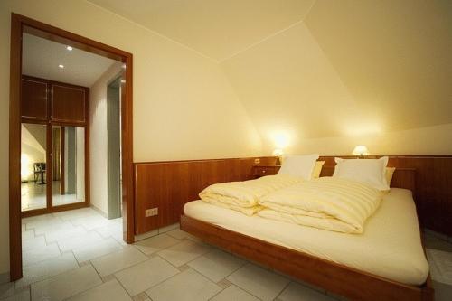 una camera da letto con un letto con coperte e cuscini bianchi di Hotel-Restaurant Moris a Walferdange