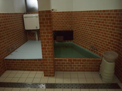 a bathroom with a tub in a brick wall at Hagurokan in Tsuruoka