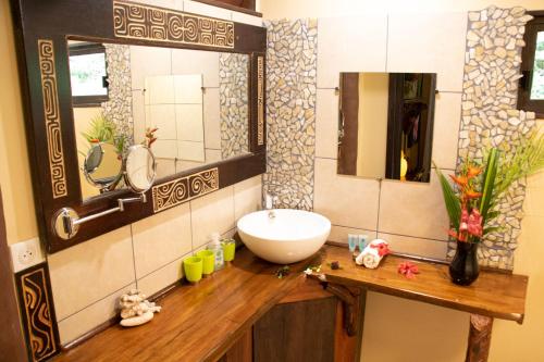a bathroom with a white sink and a mirror at Haere Mai I Te Fare in Teavaro