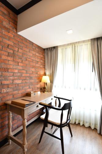 a desk and a chair in a room with a brick wall at El Barrio Lanna in Chiang Mai
