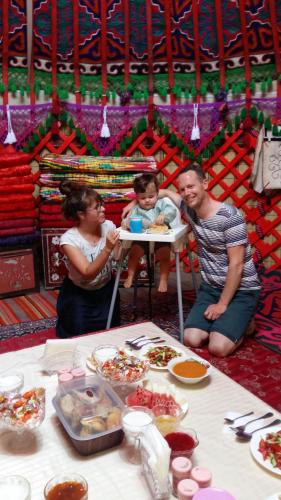 a group of people sitting around a table with food at RAHAT Guest House & Hostel in Toktogul in Toktogul