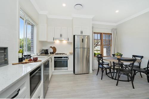 a kitchen with a table and a stainless steel refrigerator at Accommodation Hunter - Adams Street Maitland in Maitland