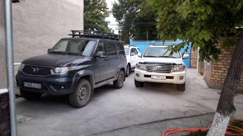 a black truck and a white truck parked next to a building at RAHAT Guest House & Hostel in Toktogul in Toktogul