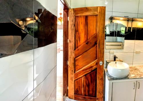 a bathroom with a wooden door and a sink at Tablas Seaview Homestay in Ferrol