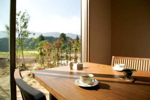 a wooden table with a cup and saucer on top of a window at Satoyama No Auberge Maki No Oto in Nanto