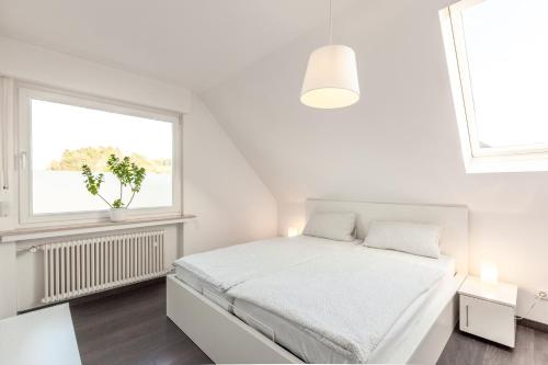 a white bedroom with a bed and a window at Architektenwohnungen mit Panoramablick bei Köln in Lindlar
