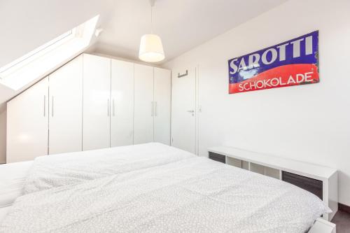a white bedroom with a bed and a sign on the wall at Architektenwohnungen mit Panoramablick bei Köln in Lindlar