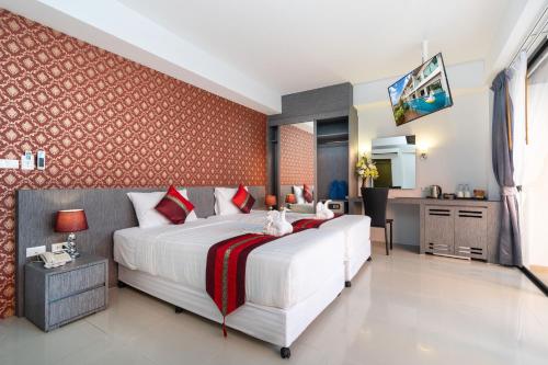 a bedroom with a large white bed and a kitchen at The Thames Pool Access Resort & Villa - SHA Extra Plus in Chalong 
