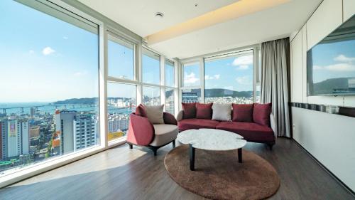 a living room with red furniture and large windows at Lavalse Hotel in Busan
