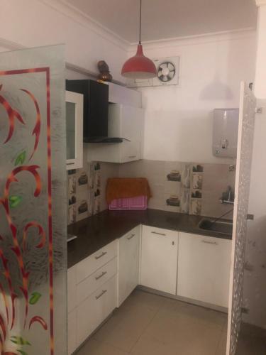 a kitchen with white cabinets and a clock on the wall at Aloha Apartments by blissful Ganges in Rishīkesh