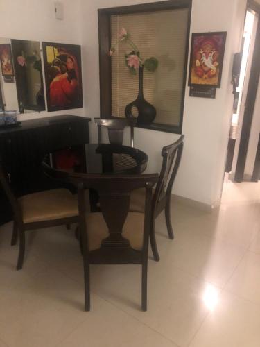 a dining room table and chair with a vase on it at Aloha Apartments by blissful Ganges in Rishīkesh