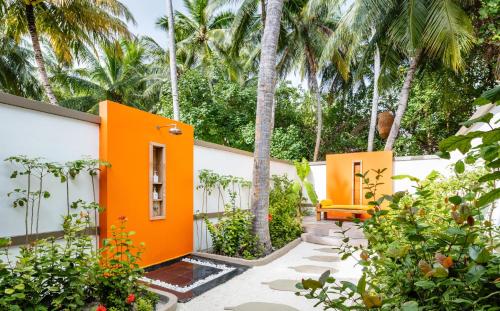 an orange house with palm trees in the background at Angsana Velavaru in Dhaalu Atoll