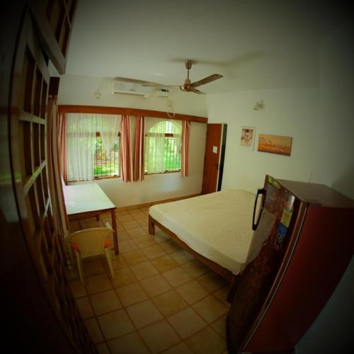 a bedroom with a bed and a table and a window at New Creation Guest House in Auroville