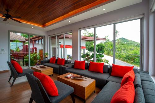 a living room with a couch and red pillows at Eranda Pool Spa Villa, Chaweng Koh Samui in Chaweng