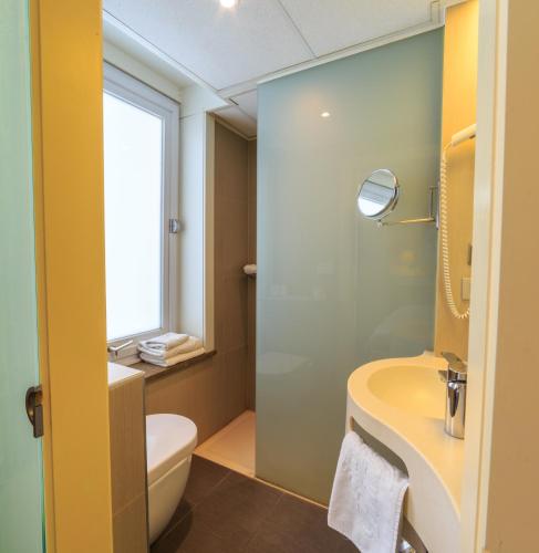 a bathroom with a sink and a toilet and a window at Hotel Pacific in Ostend