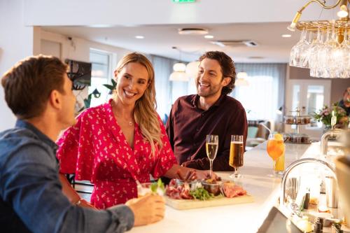 a group of people sitting at a bar with a plate of food at Welcome Hotel Barkarby in Järfälla