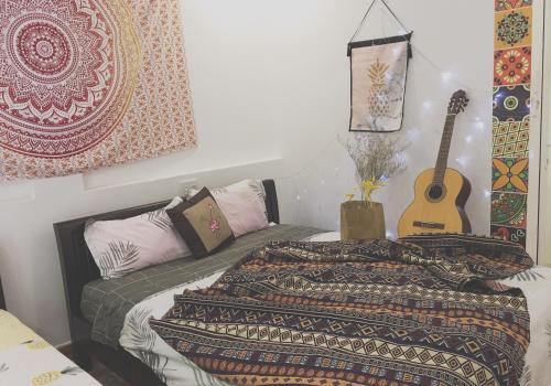 Un dormitorio con una cama y una guitarra. en Dream Flower Homestay, en Hoi An