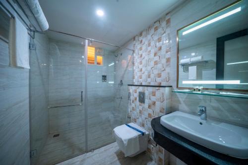 a bathroom with a glass shower and a sink at CR Grande in Madurai