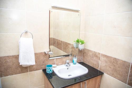 a bathroom with a sink and a mirror at West Suites Sherry Homes in Nairobi