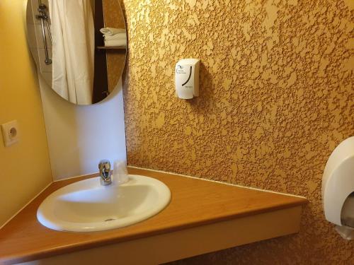 een badkamer met een wastafel en een spiegel bij Libre Hôtel in La Vespière