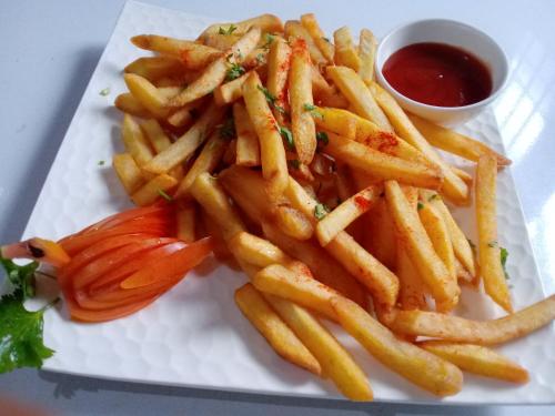 a plate with french fries and a tomato andetchup at Highland Village Resort in Dharmsala